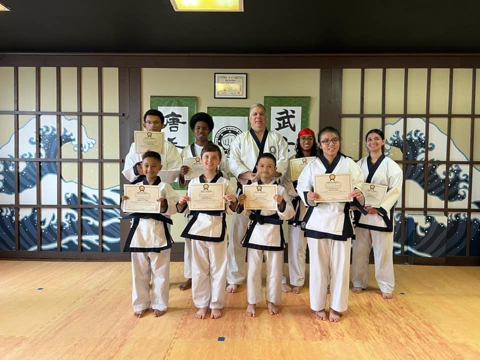 Students celebrating belt promotions with certificates